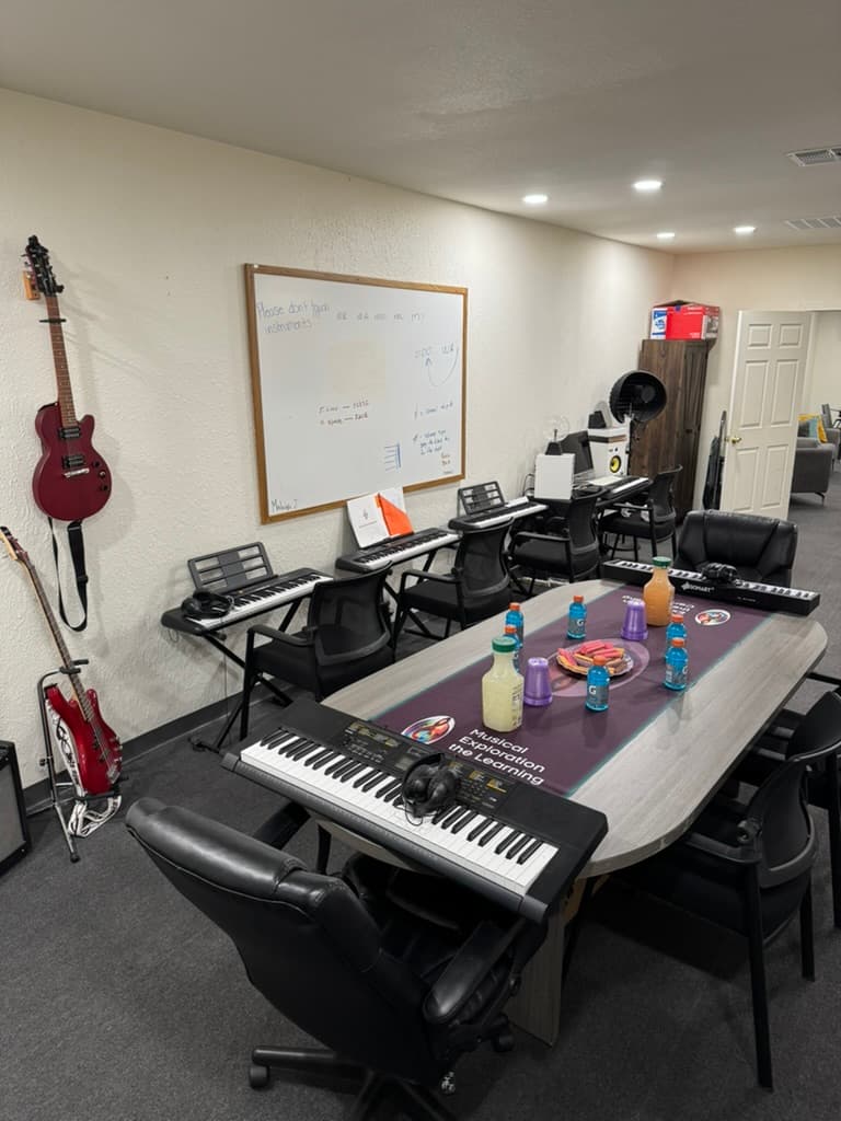 METLC classroom with keyboards, guitars, whiteboard, and group learning stations.