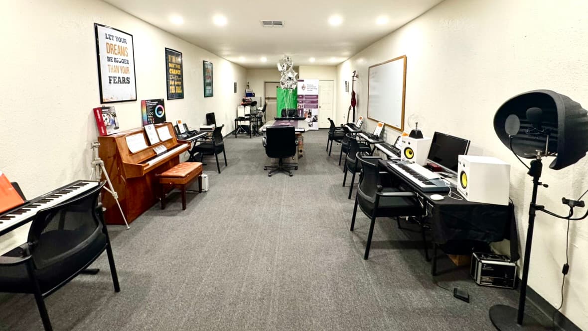 Wide view of the METLC learning center with keyboards, piano, and recording stations.